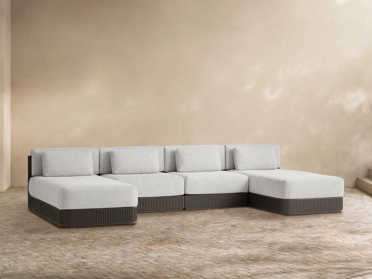 Beaumont 4-piece double chaise sectional with light gray cushions and a dark gray ribbed base, L-shaped on tiled floor.