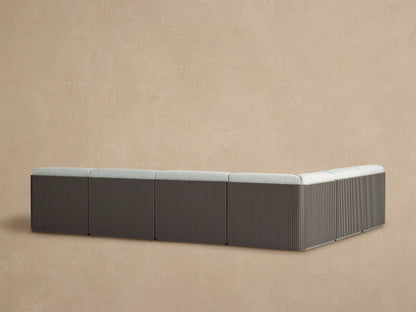 Angled close-up of Beaumont sectional with light gray textured cushions and dark brown slatted aluminum back.