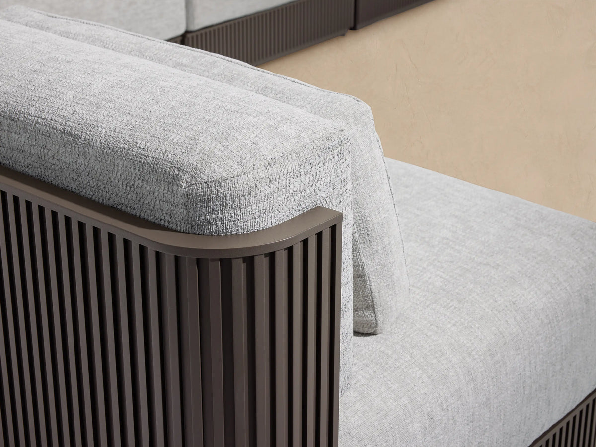 Beaumont L-shaped 6-piece outdoor sectional, light gray cushions on dark slatted aluminum frame, on a beige patio.