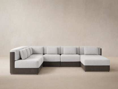L-shaped Beaumont Outdoor Aluminum Six-Piece Sectional with light grey cushions & dark ribbed aluminum frame on patio stones.