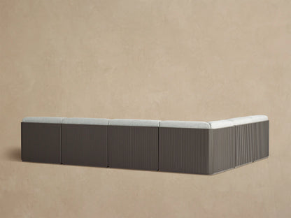 Angled view of Beaumont Outdoor Sectional with light gray textured cushions on a dark bronze slatted aluminum frame.