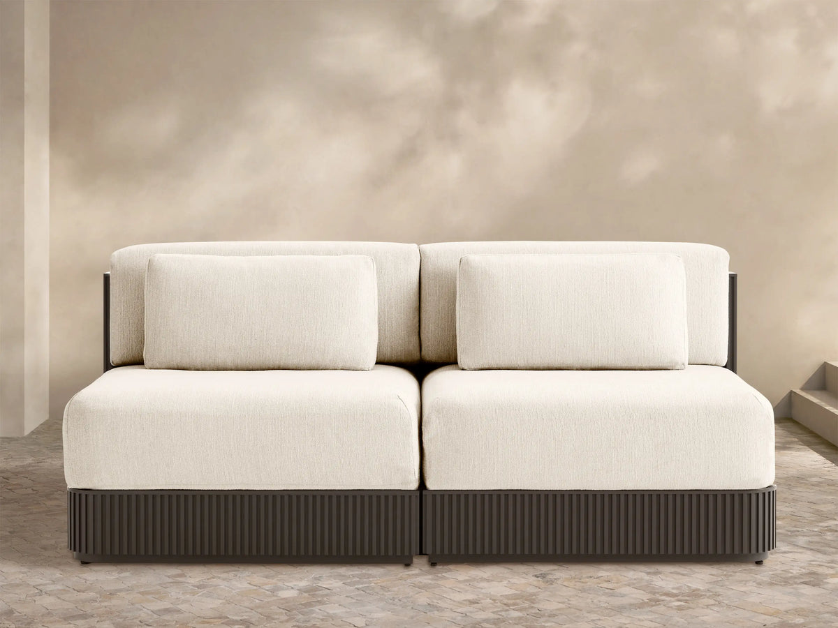 Beaumont two-piece modular sofa with light cream cushions, dark brown ribbed base, on an outdoor patio.