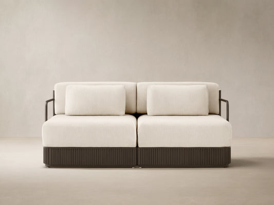 Beaumont two-piece modular sofa with light cream cushions, dark brown ribbed base, on an outdoor patio.