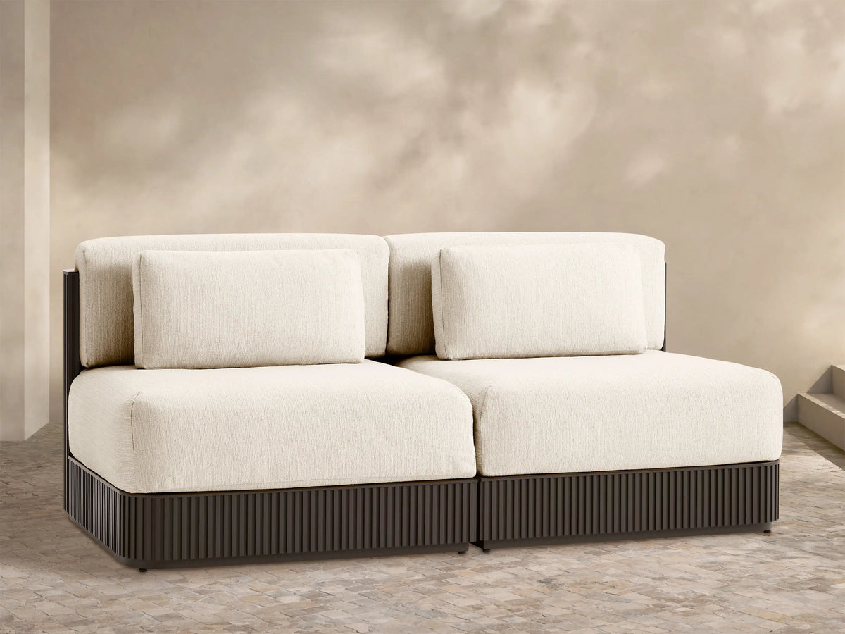 Beaumont two-piece modular sofa with light cream cushions, dark brown ribbed base, on an outdoor patio.