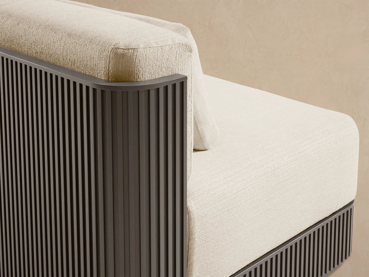 Beaumont Outdoor Aluminum Two-Piece Modular Sofa with light cream cushions & dark brown slatted base on a patio.