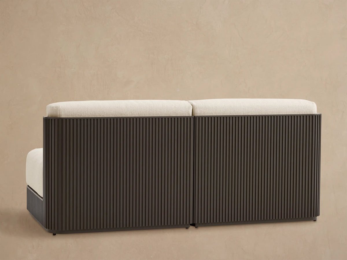 Beaumont Outdoor Aluminum Sofa: Angled close-up of light beige cushions on a dark gray slatted aluminum frame.