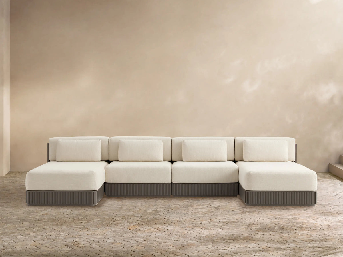 Beaumont 4-piece outdoor double chaise sectional, cream cushions, dark gray ridged aluminum base, facing forward on a patio.