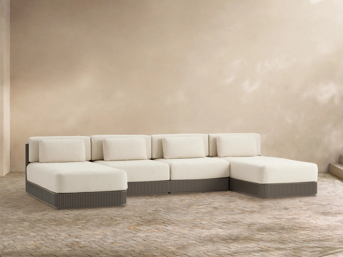 Beaumont 4-piece outdoor double chaise sectional, cream cushions, dark gray ridged aluminum base, facing forward on a patio.