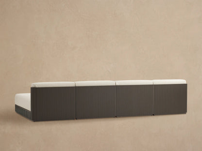 Close-up of Beaumont sectional's dark gray slatted aluminum frame and light beige textured cushions, viewed from above.