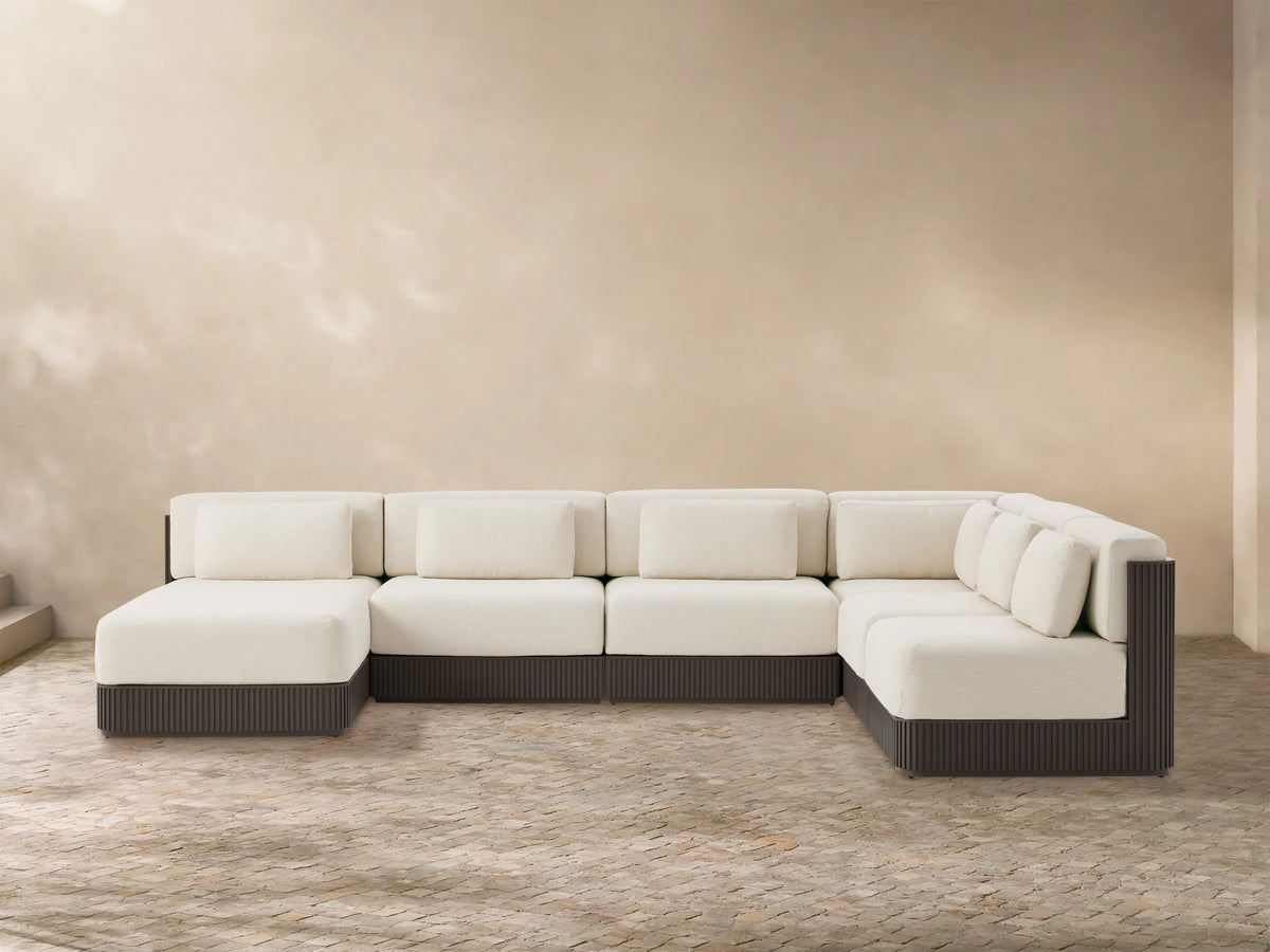 Beaumont six-piece L-shaped outdoor sectional with cream cushions, dark brown slatted aluminum base, on a stone patio.