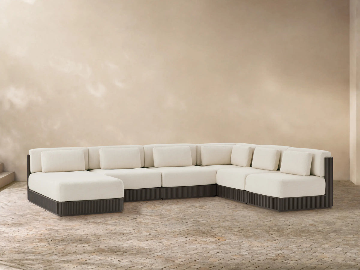 Beaumont six-piece L-shaped outdoor sectional with cream cushions, dark brown slatted aluminum base, on a stone patio.