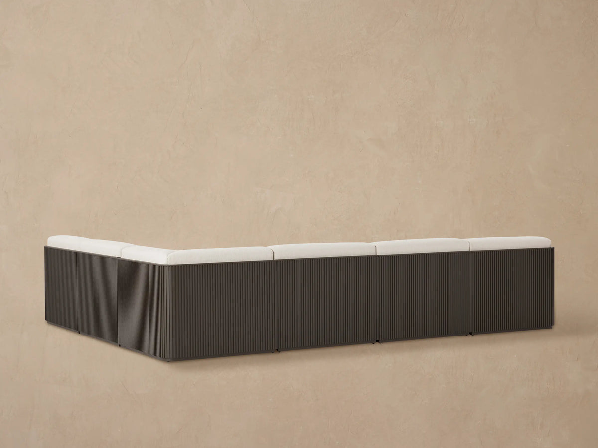 Close-up of Beaumont sectional's light beige textured cushions on a dark slatted aluminum frame, viewed from above.