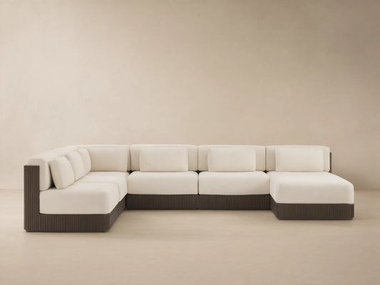 Beaumont six-piece L-shaped outdoor sectional with cream cushions, dark brown slatted aluminum base, on a stone patio.