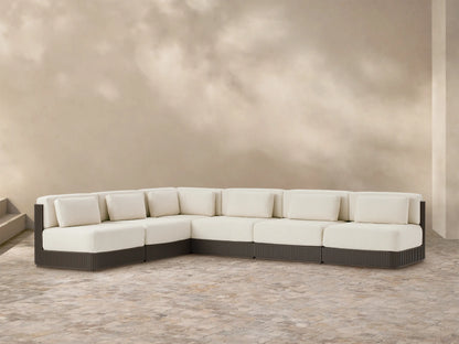 Beaumont Outdoor Aluminum Six-Piece Sectional. L-shaped, with cream cushions & dark slatted aluminum base on a tiled patio.