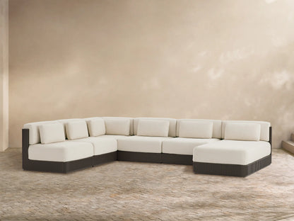 Beaumont 6-pc U-shaped outdoor sectional with right chaise. Cream cushions, dark ribbed base, on a stone patio with beige wall.