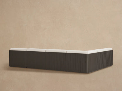 Close-up of Beaumont Outdoor Sectional with light textured cushions, dark slatted aluminum frame with curved top.