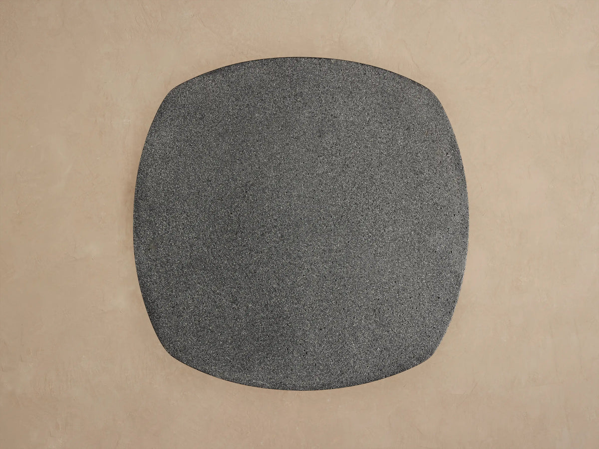 Angled close-up of Bellagio Outdoor End Table. Dark gray, speckled rounded top & textured, patterned cylindrical base.