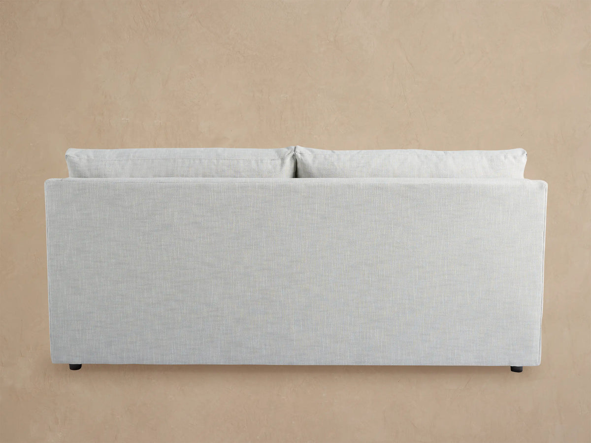 Light gray Branson Outdoor Sofa with two seat and two back cushions, modern clean lines, against a wooden shingle wall.