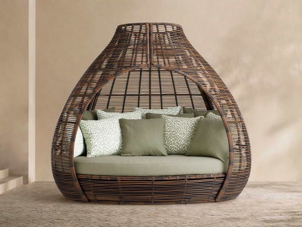 Calusa Outdoor Daybed in Eden Sage: brown woven wicker enclosed design with light green cushion and patterned toss pillows.