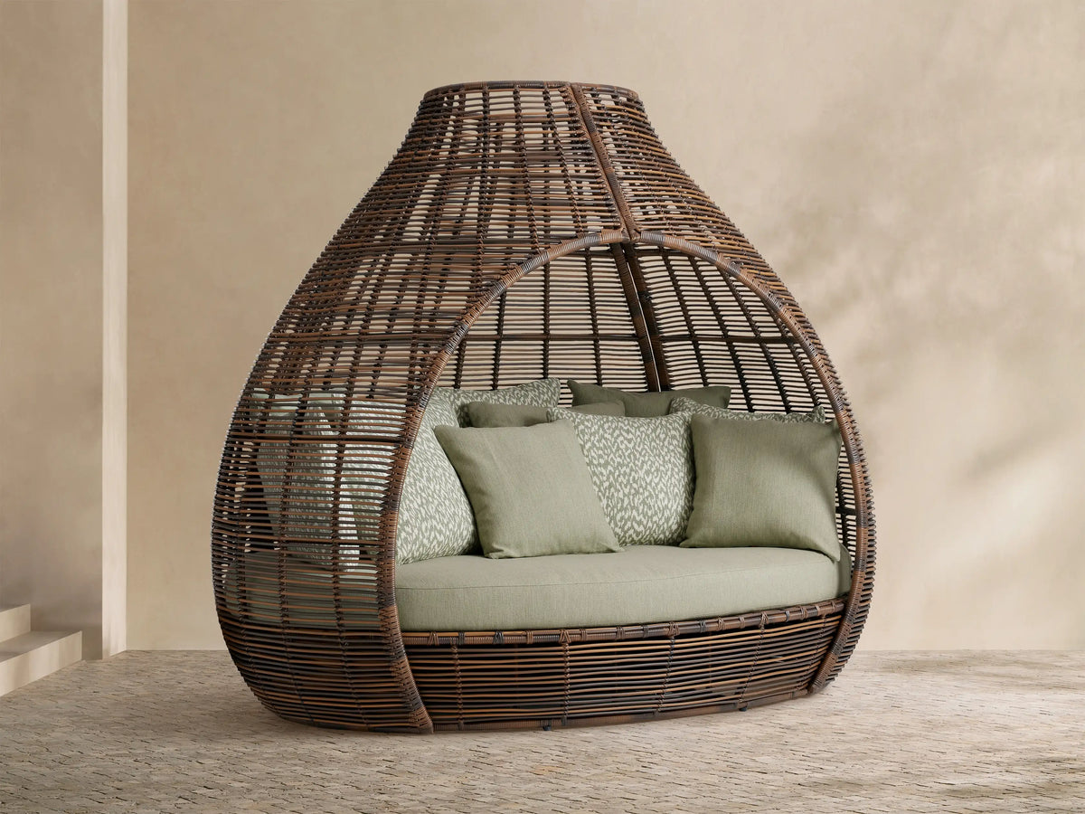Calusa Outdoor Daybed in Eden Sage: brown woven wicker enclosed design with light green cushion and patterned toss pillows.