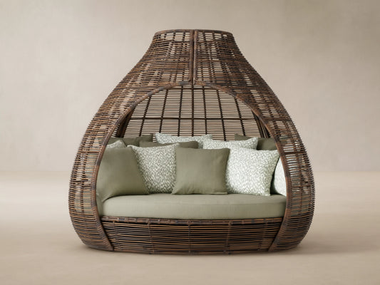 Calusa Outdoor Daybed in Eden Sage: brown woven wicker enclosed design with light green cushion and patterned toss pillows.