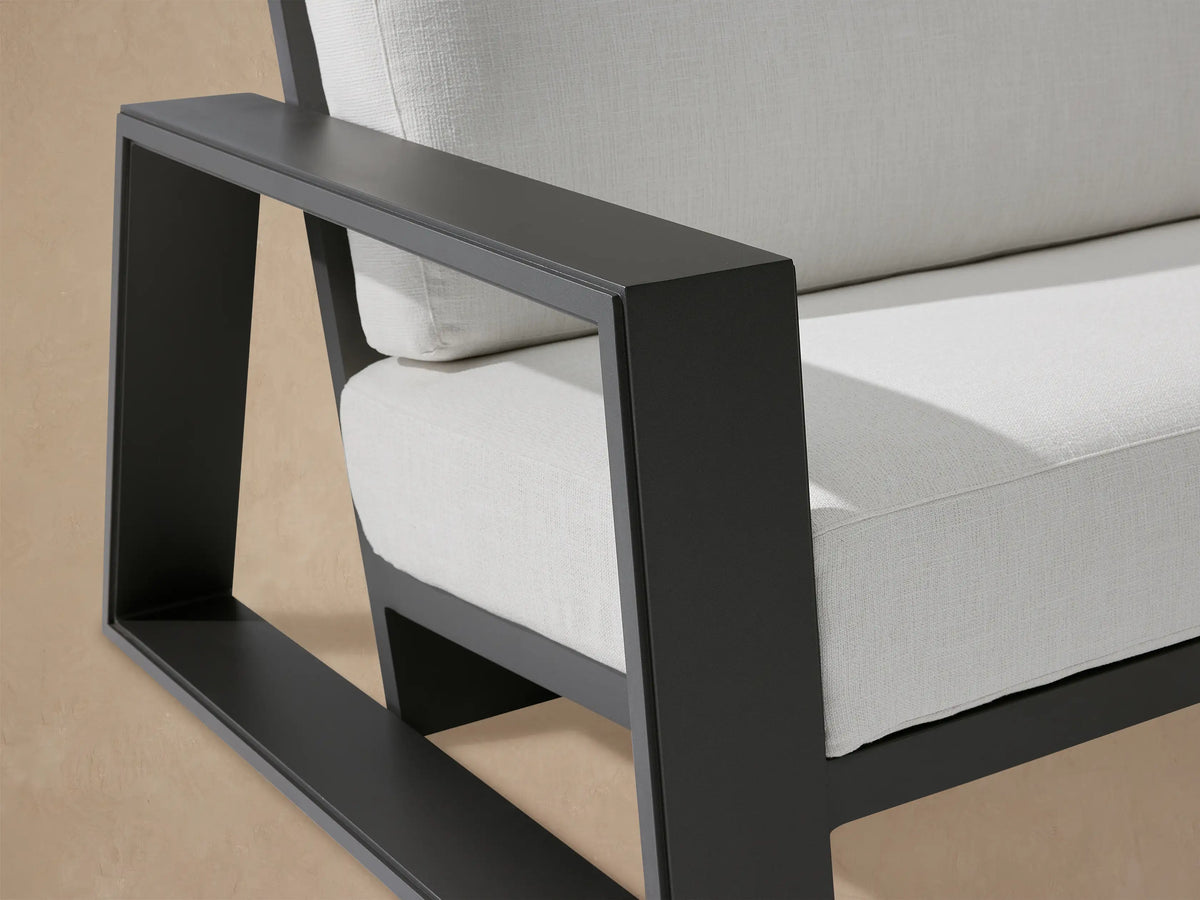 Canyon Outdoor Aluminum Sofa, dark gray aluminum frame with two thick white cushions, in an outdoor patio setting.