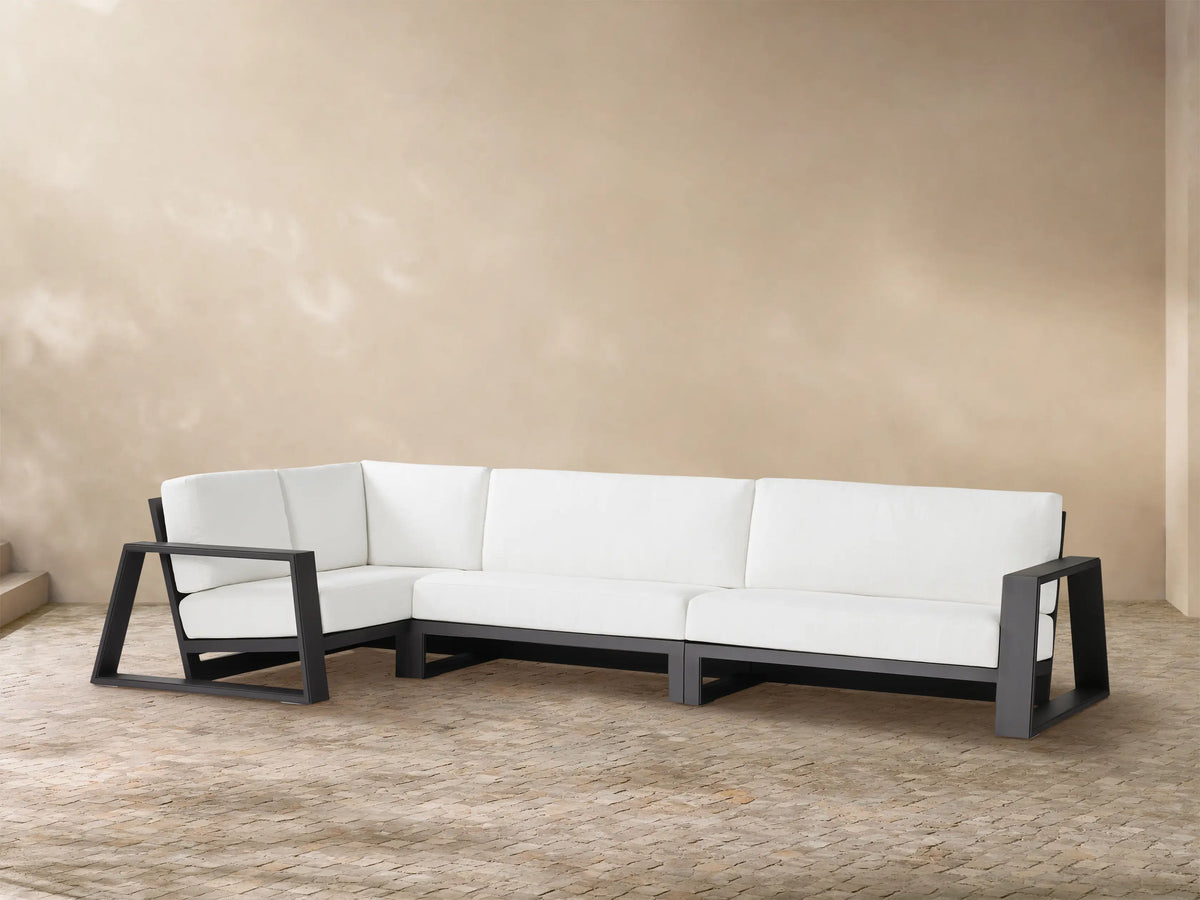 Canyon Outdoor Aluminum L-shaped three-piece sectional with dark gray frames and white cushions on a light-colored patio.