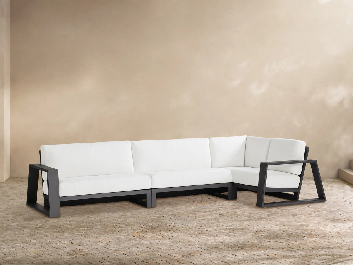 L-shaped Canyon Outdoor Aluminum Three-Piece Sectional with dark gray frames & white cushions on a textured patio.