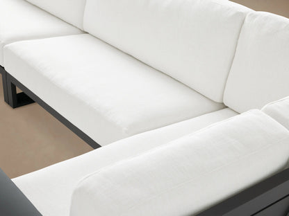 L-shaped Canyon Outdoor Aluminum Three-Piece Sectional with sleek black frames and thick white cushions on a paver patio.
