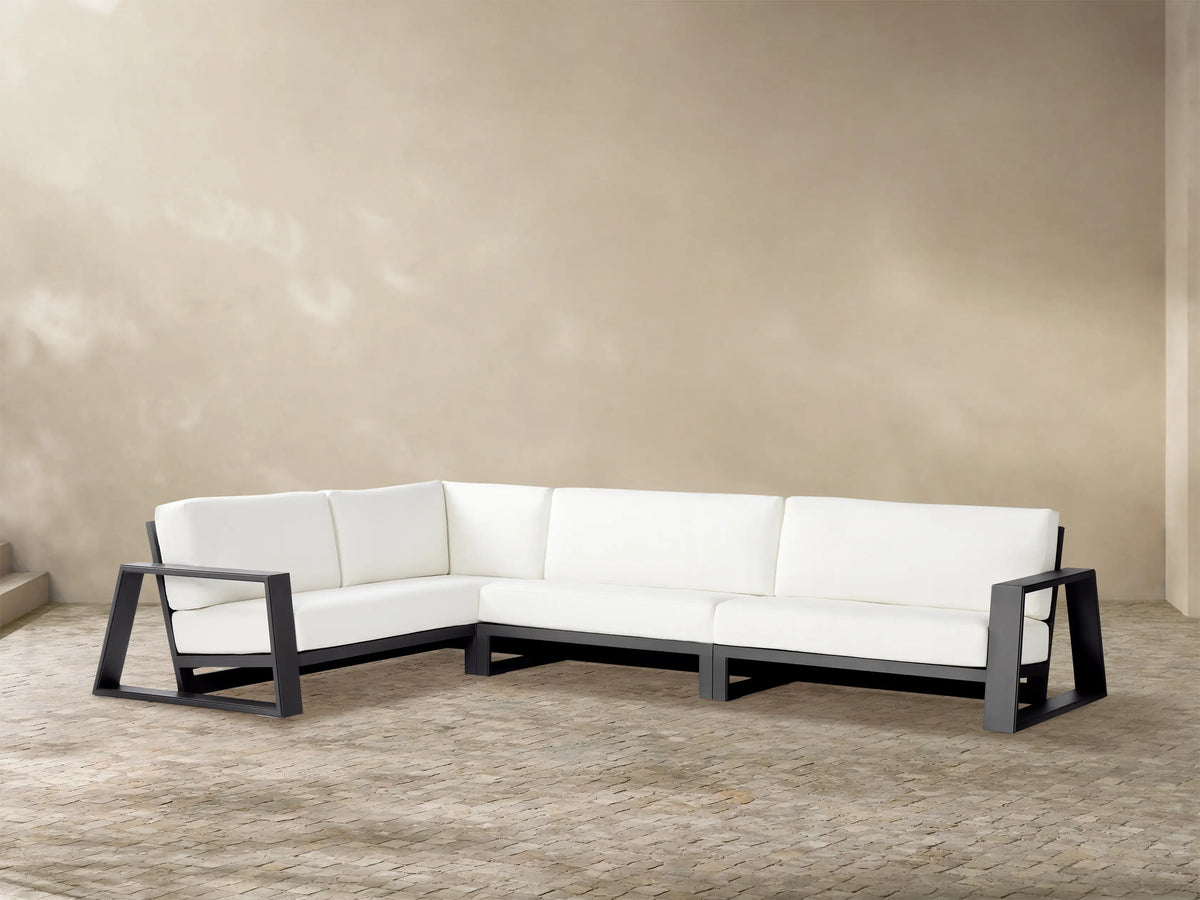 Canyon Outdoor Aluminum Three-Piece Sectional, L-shaped, dark gray frame, white cushions, on a stone patio.