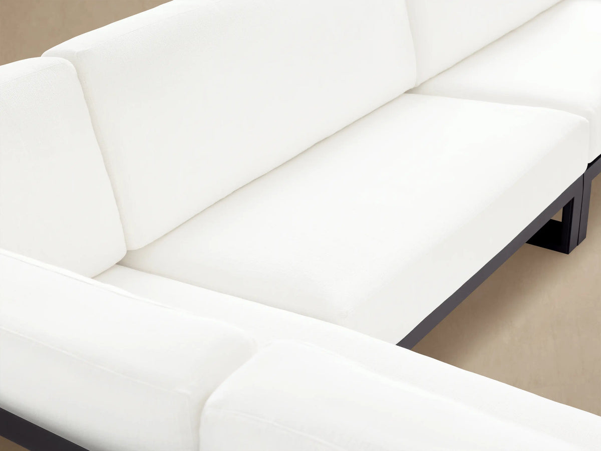 L-shaped Canyon Outdoor Aluminum Three-Piece Sectional with dark gray frames and thick white cushions on a stone patio.