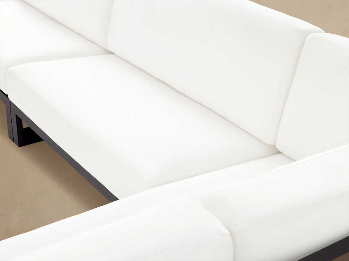 Canyon Outdoor Aluminum Three-Piece Sectional, L-shaped with dark gray frame and white cushions, on a light-colored patio.