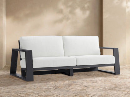 Canyon Outdoor Aluminum Sofa: 2-seater, dark gray aluminum frame, white cushions, viewed straight on against a light tan wall.