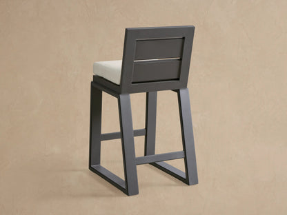 Close-up of a Canyon Outdoor Aluminum Barstool's dark gray frame and light beige textured seat cushion.