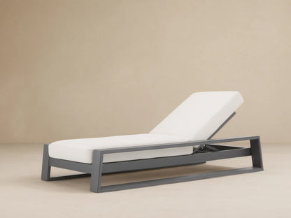 Canyon Outdoor Aluminum Chaise with dark gray frame and white cushions, backrest elevated, angled view on light brown patio.