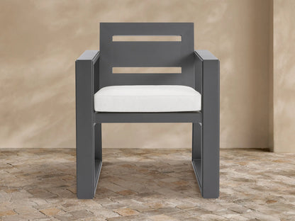 Canyon aluminum dining arm chair, dark gray geometric frame, two horizontal back slats, white seat cushion on stone patio.