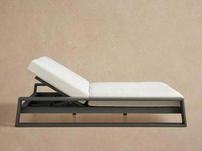 Canyon Outdoor Aluminum Double Chaise with a charcoal frame & two white cushions, both backrests angled up, on a patio.