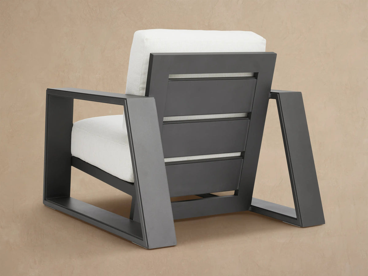 Canyon Outdoor Aluminum Lounge Chair with dark gray aluminum frame, wide armrest, thick white textured seat and back cushions.