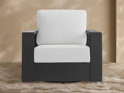 Modern Canyon Outdoor Aluminum Swivel Chair with dark grey frame and plush light cream cushions, angled on a patio.