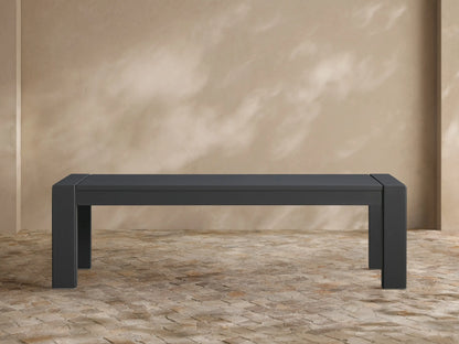Dark gray Canyon Outdoor Aluminum Dining Bench, modern rectangular design, on a tiled patio against a tan wall.