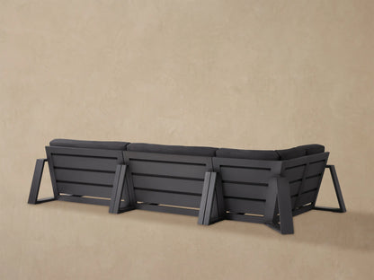 Angled close-up of a dark gray Canyon Outdoor Aluminum Three-Piece Sectional's corner, highlighting its cushions and dark frame.