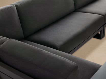 Canyon Outdoor Aluminum Three-Piece Sectional, L-shaped, with sleek dark gray aluminum frame and matching cushions, on a stone patio.