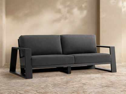 Canyon Outdoor Aluminum Sofa: Modern 2-seater with dark gray cushions and sleek dark gray aluminum frame on a stone patio.