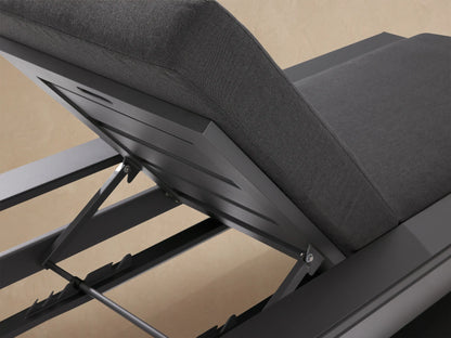 Canyon Outdoor Aluminum Chaise with charcoal gray frame and cushions. Backrest angled up, side view against a beige wall.