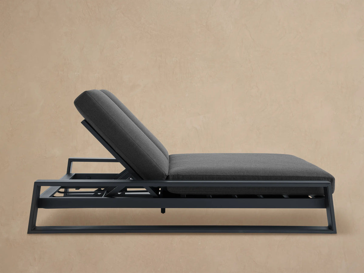 Modern Canyon Outdoor Double Chaise with dark gray aluminum frame & cushions, both backrests inclined, on a paved patio.