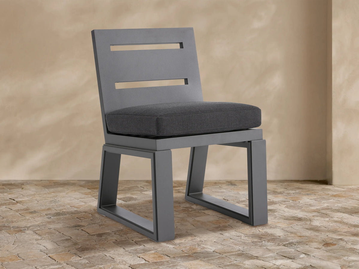 Canyon Outdoor Aluminum Dining Side Chair. Modern dark gray aluminum chair with two horizontal back slats & gray cushion on tiled floor.