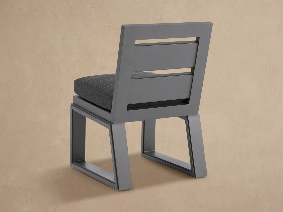 Angled close-up of a Canyon Outdoor Dining Side Chair with dark gray aluminum frame & thick dark gray seat cushion.