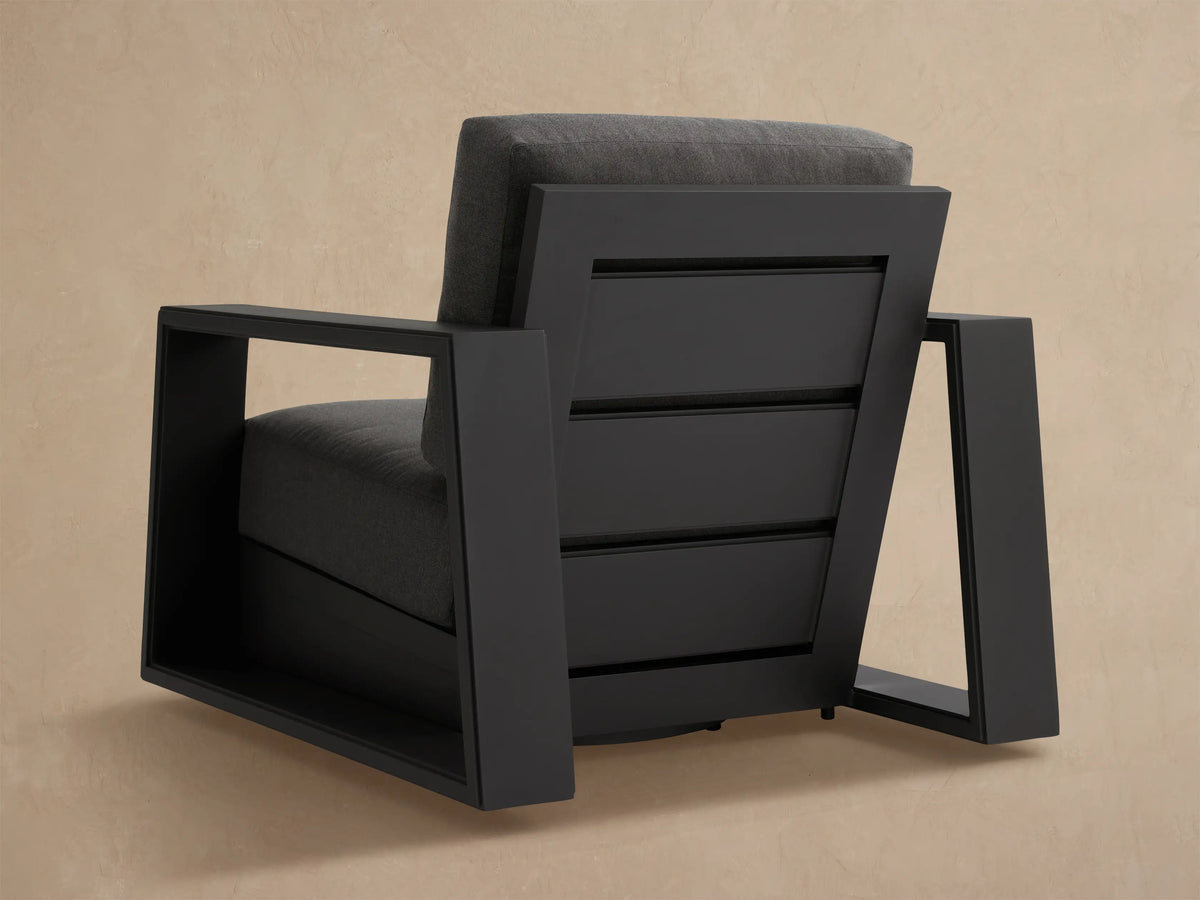 Close-up of Canyon Outdoor Aluminum Swivel Chair's dark grey slatted back frame, showing textured cushion.