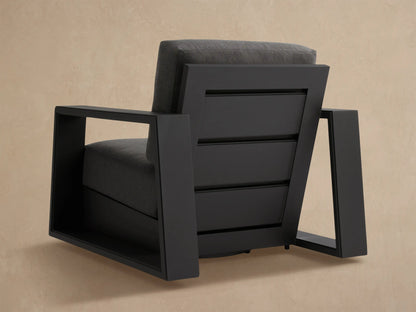 Close-up of Canyon Outdoor Aluminum Swivel Chair's dark grey slatted back frame, showing textured cushion.