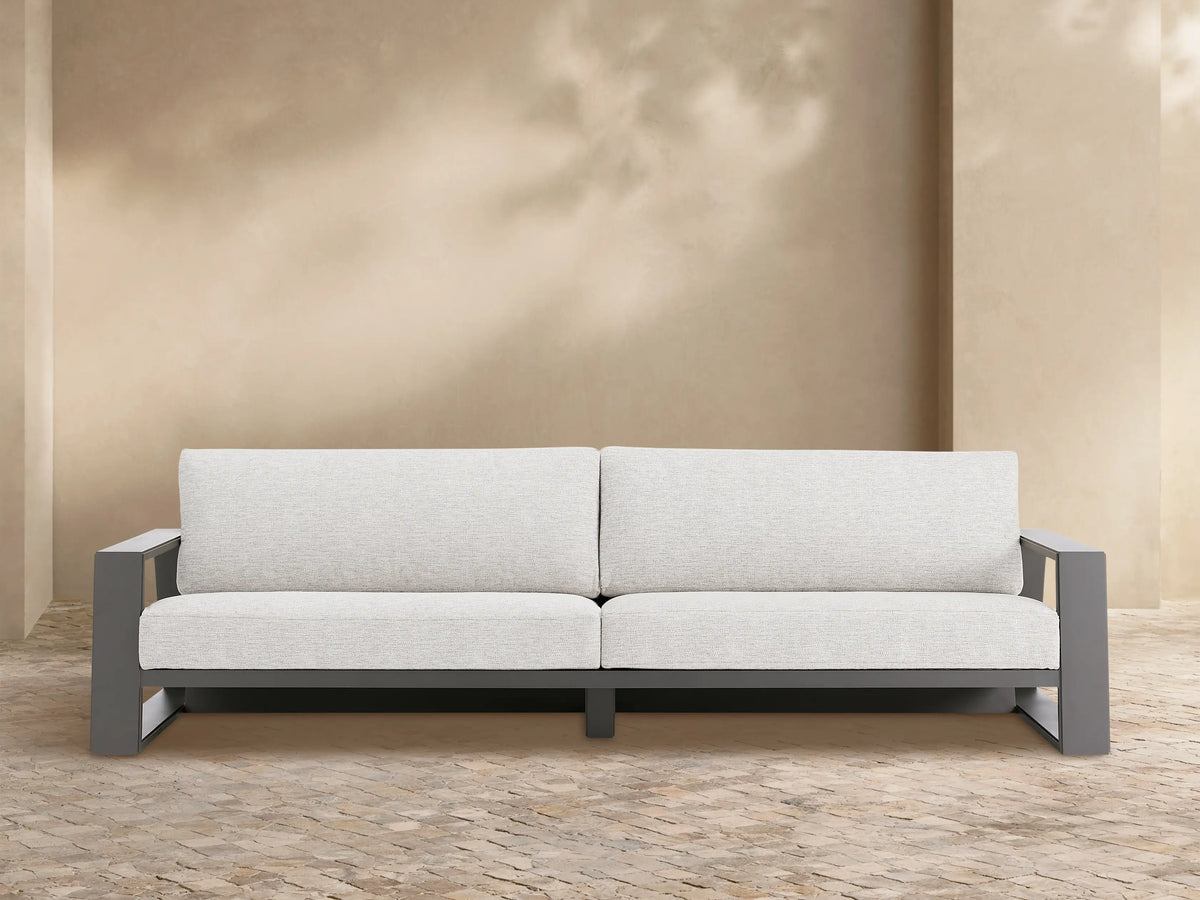 Canyon Outdoor Aluminum Sofa, two-seater, with a dark gray frame and light gray cushions on a patio setting.
